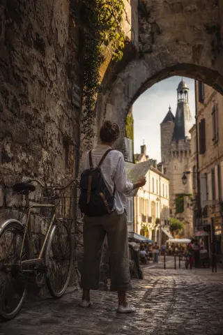 Art historian sketching quietly on a stone bench amid sunlit cloister gardens at Val-de-Bénédiction, surrounded by aged stone arches and soft greenery at golden hour.